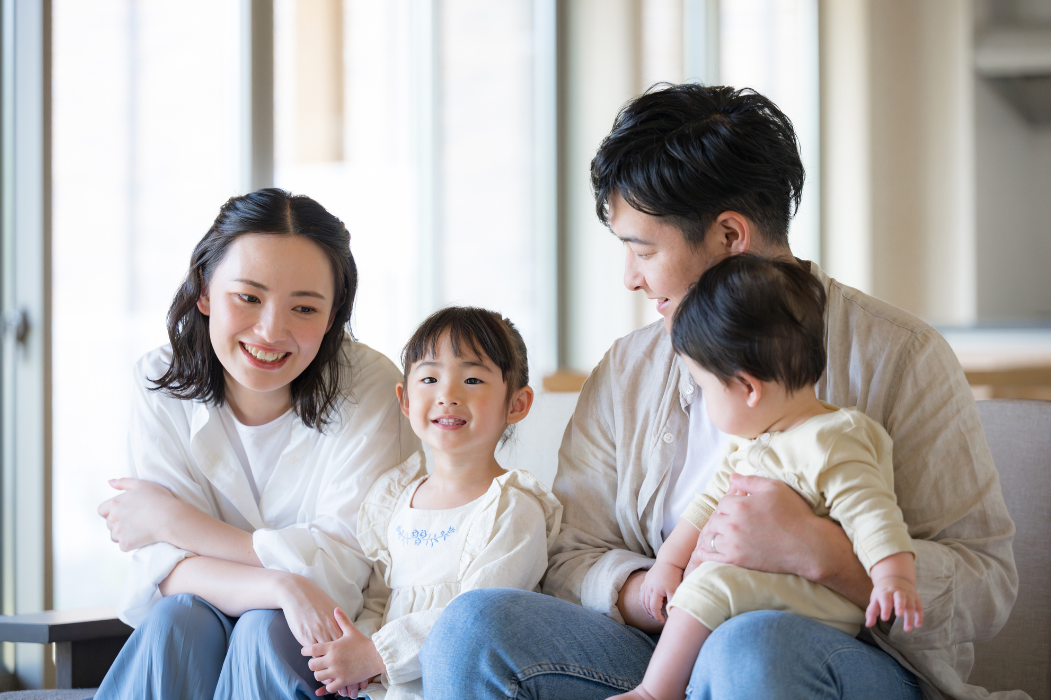 家族4人がリビングで笑顔で過ごしている画像